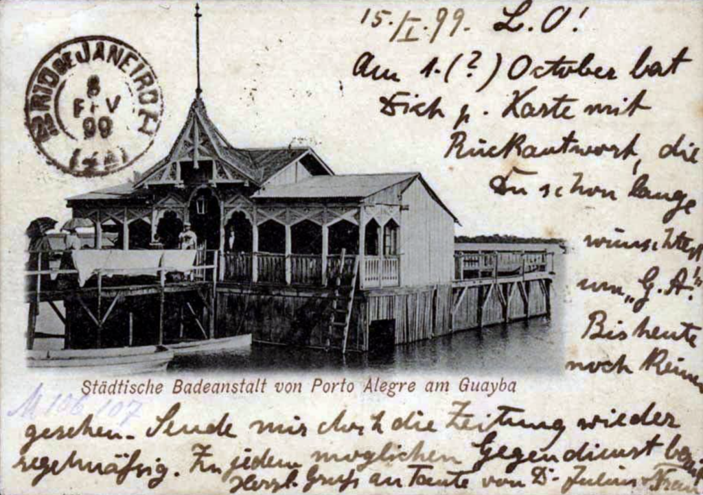 Imagem de um cartão postal com uma casa de madeira com macesso ao rio, com várioas coisas escritas à mão em alemão
